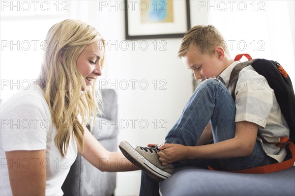 Mother helping son (6-7) tying shoes
