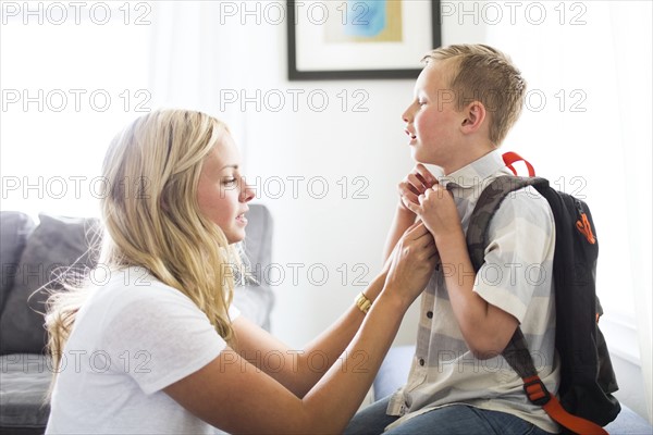 Mother helping son (6-7) buttoning shirt