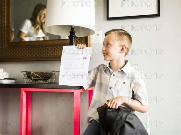 Smiling boy (6-7) showing schoolpaper