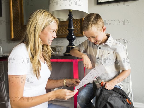 Smiling boy (6-7) showing schoolpaper to mother