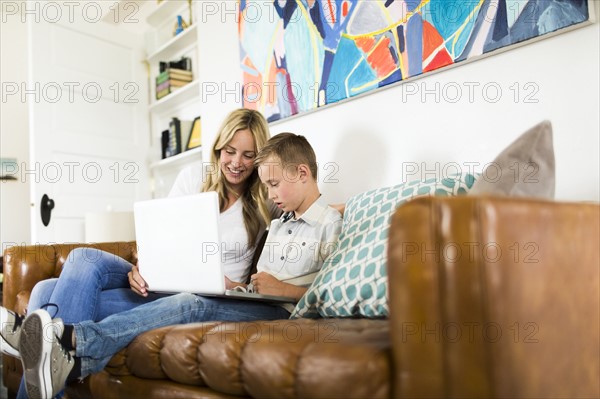 Boy (6-7) with mother using laptop on sofa