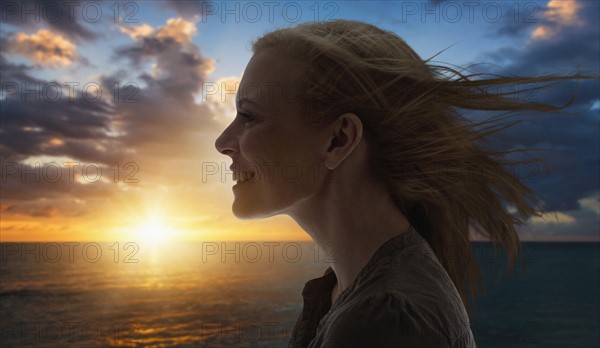 Portrait of woman by sea at sunset.