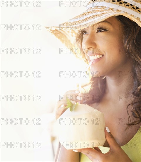 Young woman having drink in sunlight.