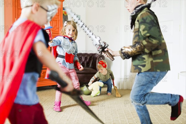 Children (2-3, 4-5, 6-7) wearing superhero costumes playing at home