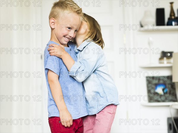 Little girl (4-5) whispering into brother's (4-5) ear