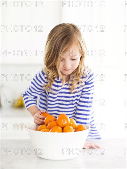 Girl (4-5) looking at oranges, smiling