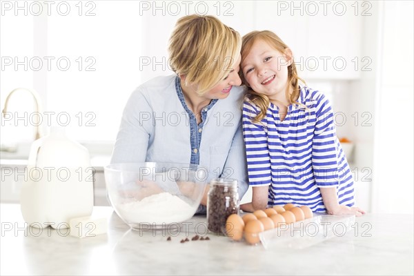 Portrait of girl (4-5) spending time with mom in kitchen