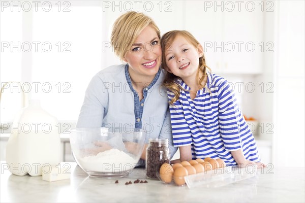 Portrait of girl (4-5) spending time with mom in kitchen