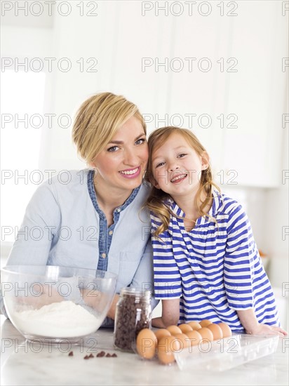 Portrait of girl (4-5) spending time with mom in kitchen