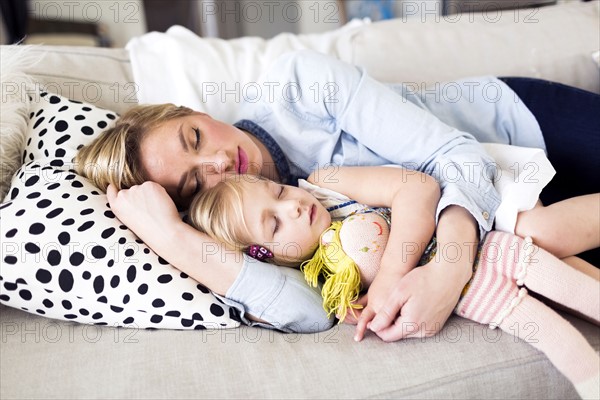 Mother and daughter (2-3) sleeping on sofa