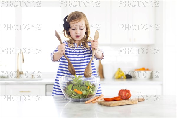 Girl (4-5) mixing salad