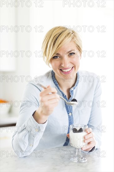 Portrait of woman eating yogurt with blackberries