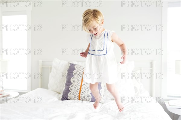 Girl (2-3) jumping on bed