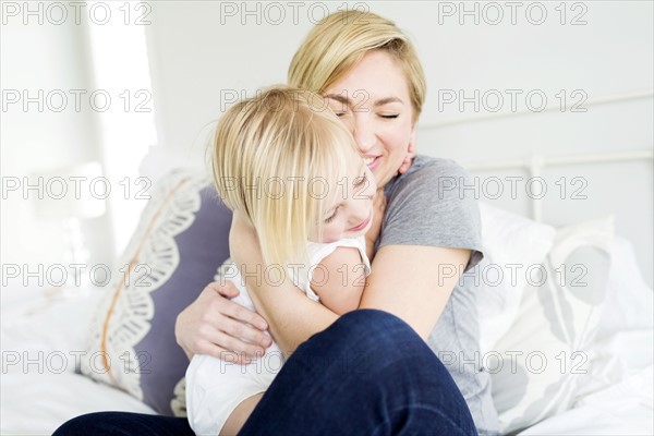 Woman hugging daughter (2-3) in bedroom