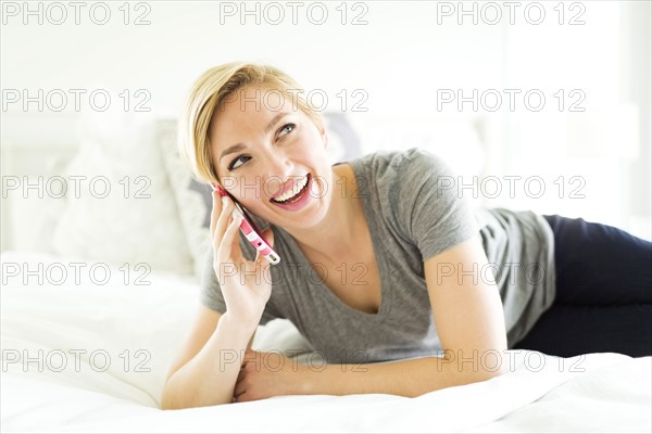 Mid-adult woman talking on phone in bedroom