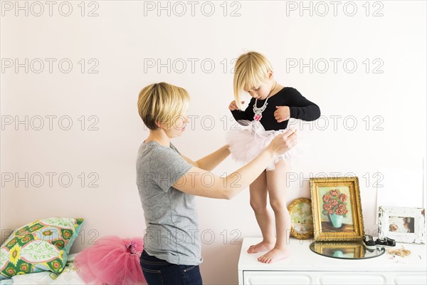 Woman helping daughter (4-5) with costume