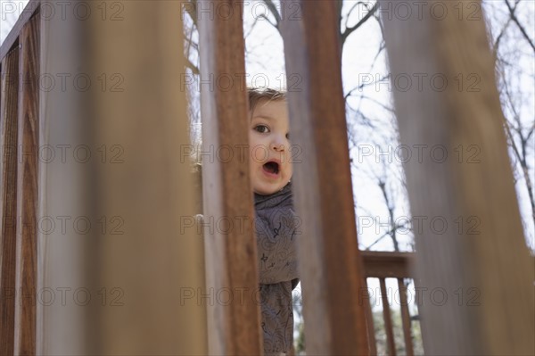 Portrait of girl hiding behind fence