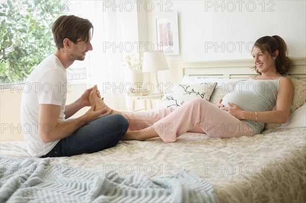 Man massaging pregnant woman's feet.