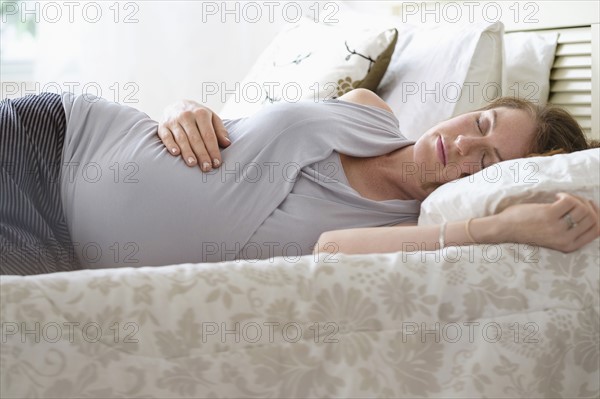 Pregnant woman sleeping in bed.