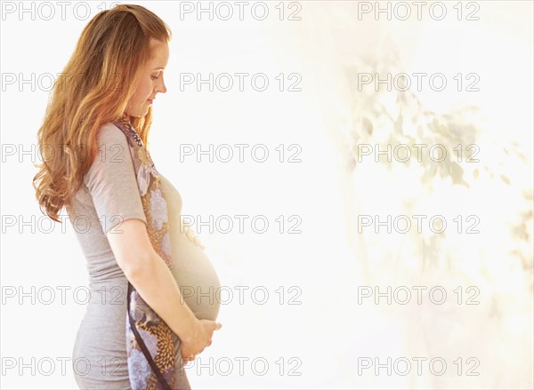 Side view of pregnant woman outdoors.
