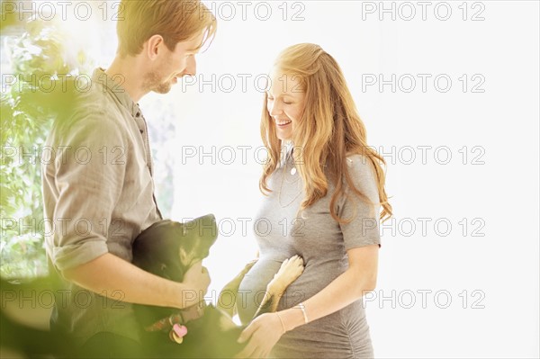 Mid-adult couple playing with dog.