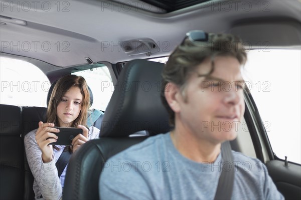 Girl (10-11) texting in back seat.