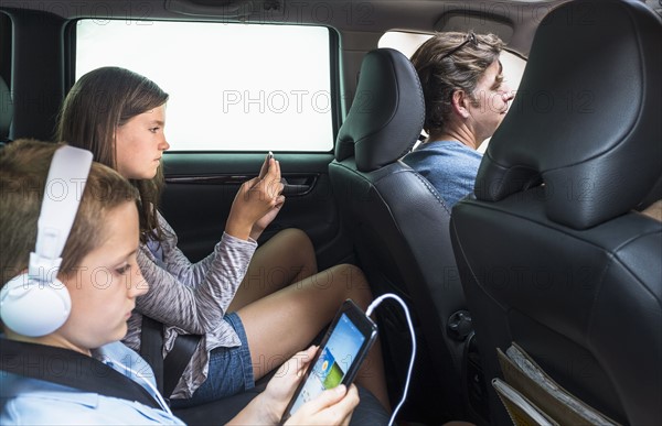 Children (8-9, 10-11) texting in back seat.