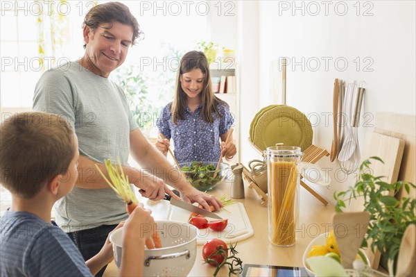 Children (8-9, 10-11) preparing food with their father.