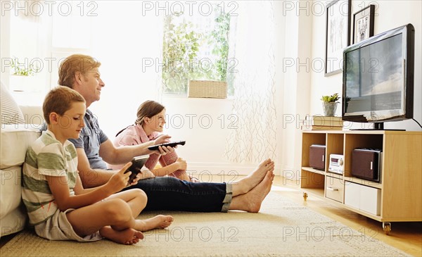 Children (8-9, 10-11) watching TV with their father.