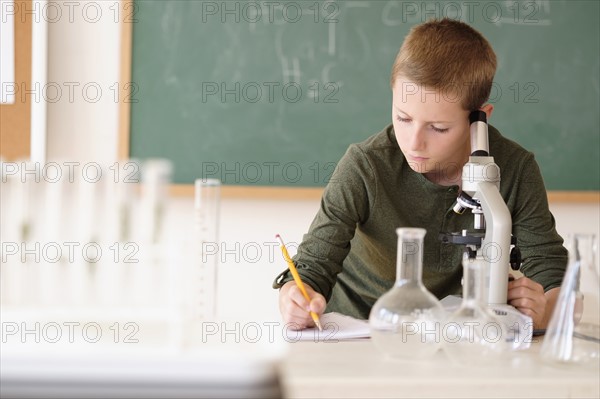 Boy (8-9) taking notes in classroom.