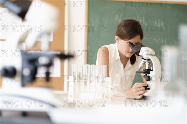 Girl (10-11) using microscope.