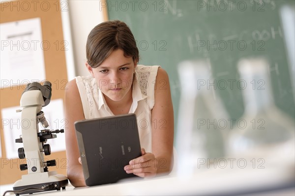 Girl (10-11) using tablet pc in classroom.