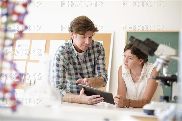 Teacher talking with girl (10-11) in classroom.