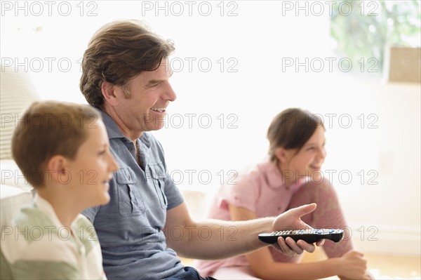 Children (8-9, 10-11) watching TV with their father.