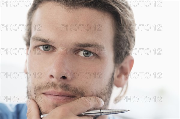 Portrait of mid-adult businessman with pen.