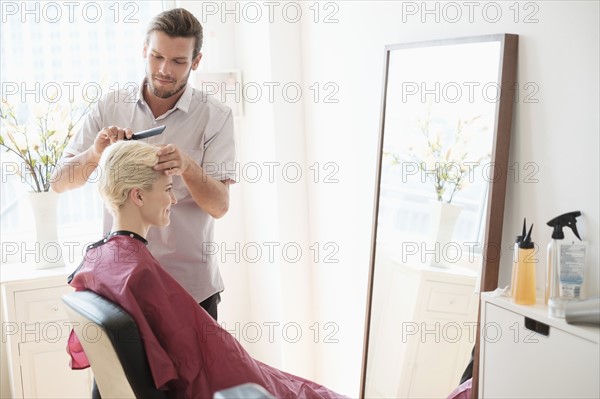 Hairdresser combing woman's hair.