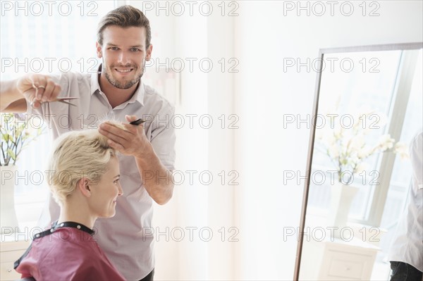 Portrait of hairdresser cutting woman's hair.