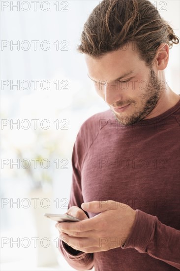 Mid-adult man texting indoors.