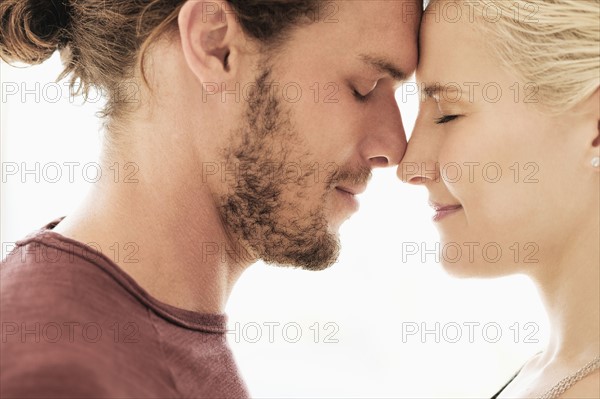 Couple rubbing noses on white background.
