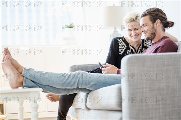 Couple laughing on sofa.