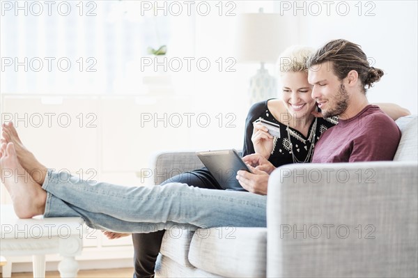 Couple using tablet pc on sofa.