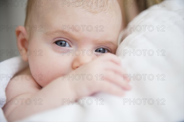 Portrait of baby girl (2-5 months) in mother's arms