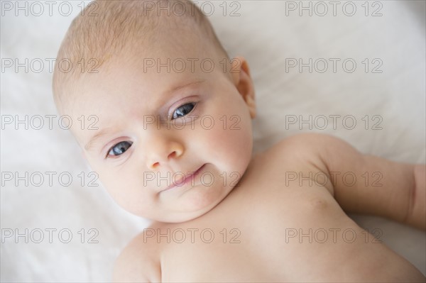 Baby girl (2-5 months) lying on bed