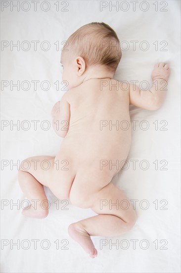 Baby girl (2-5 months) crouching on bed