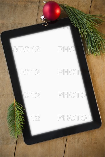 Studio shot of blank tablet and Christmas decoration on wood