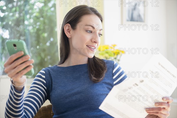 Woman with document and Smartphone at home