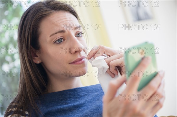 Woman with tissue watching Smartphone