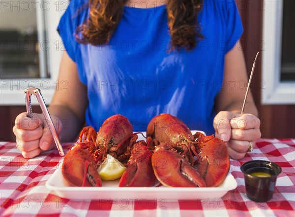 View of table with lobster meal and woman preparing to eat