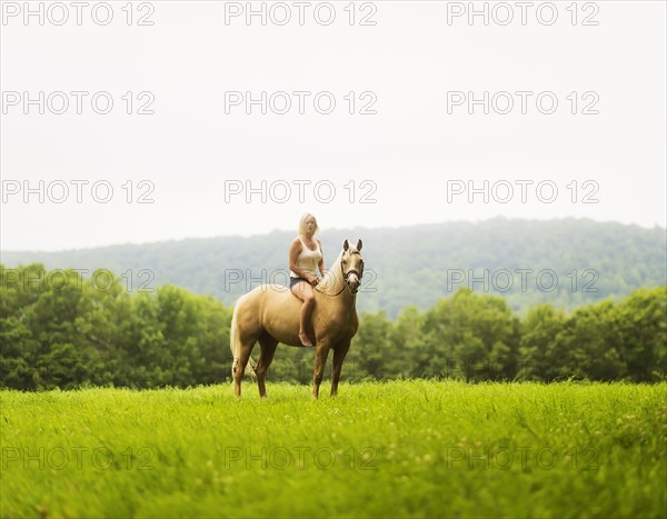 Woman horseback riding in countryside