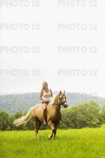 Woman horseback riding in countryside